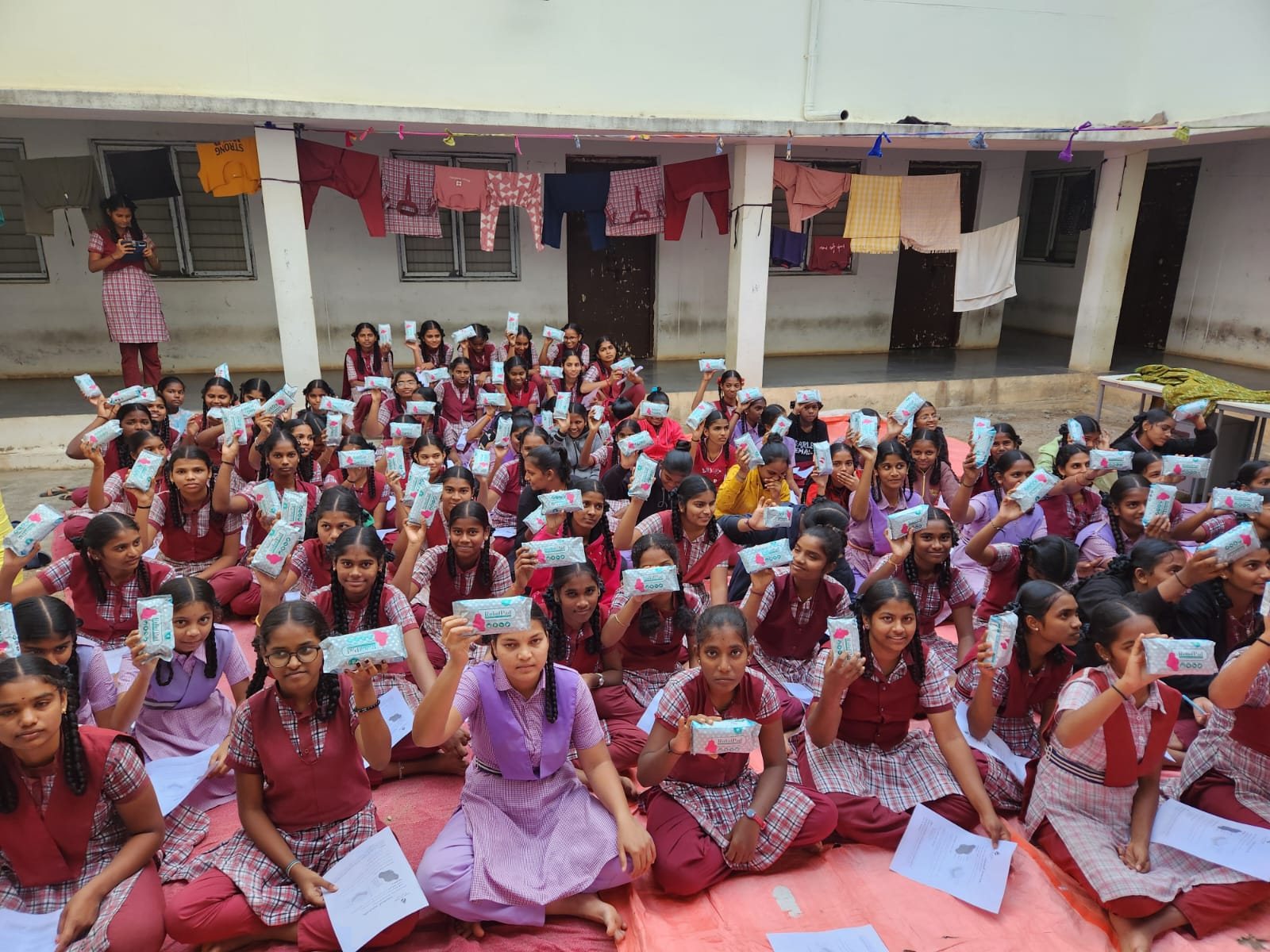Girls gathered in a school courtyard during a Care-O-Safe pad distribution